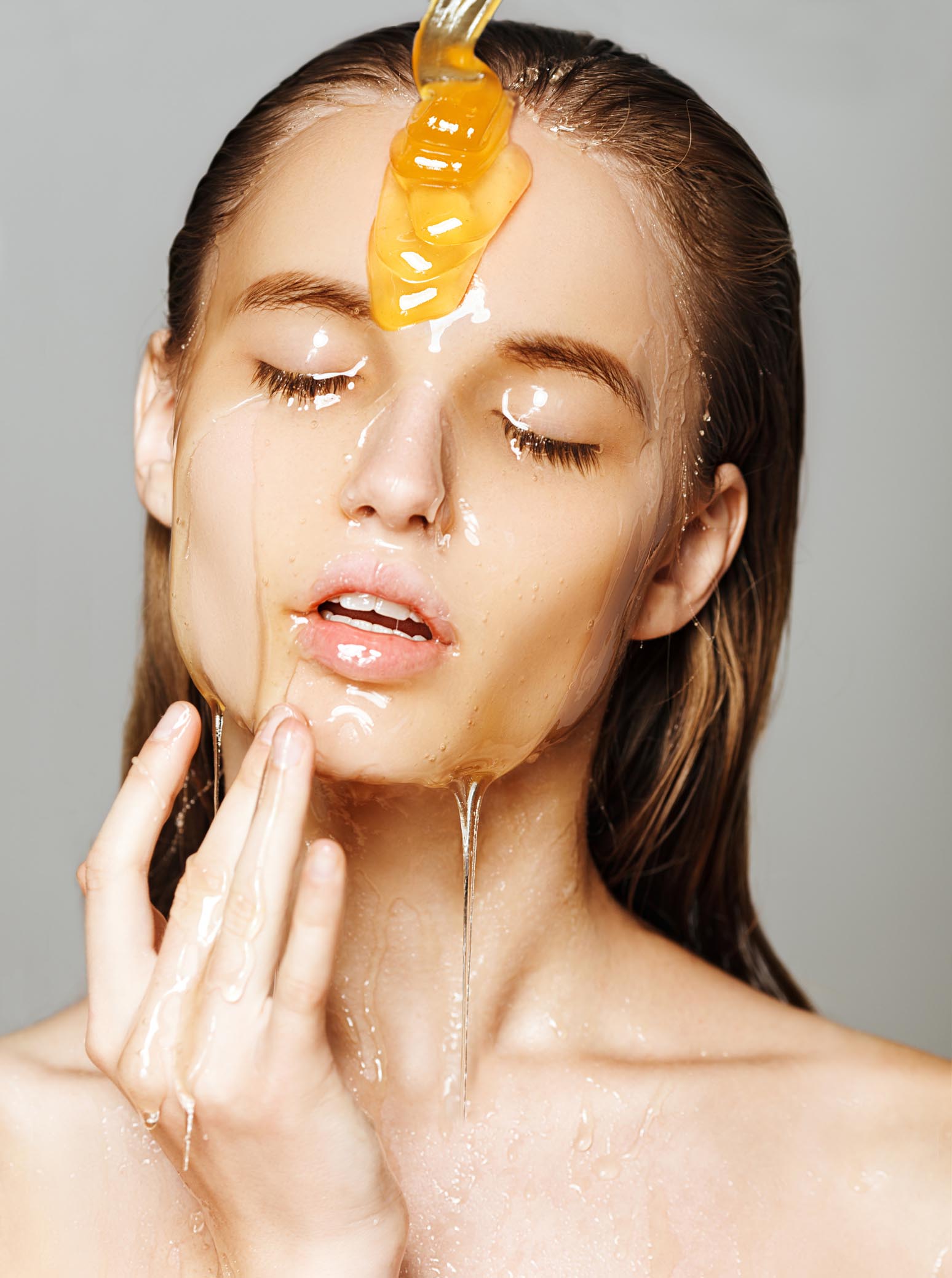 Beautiful woman with honey on her face. Healthy perfect skin.